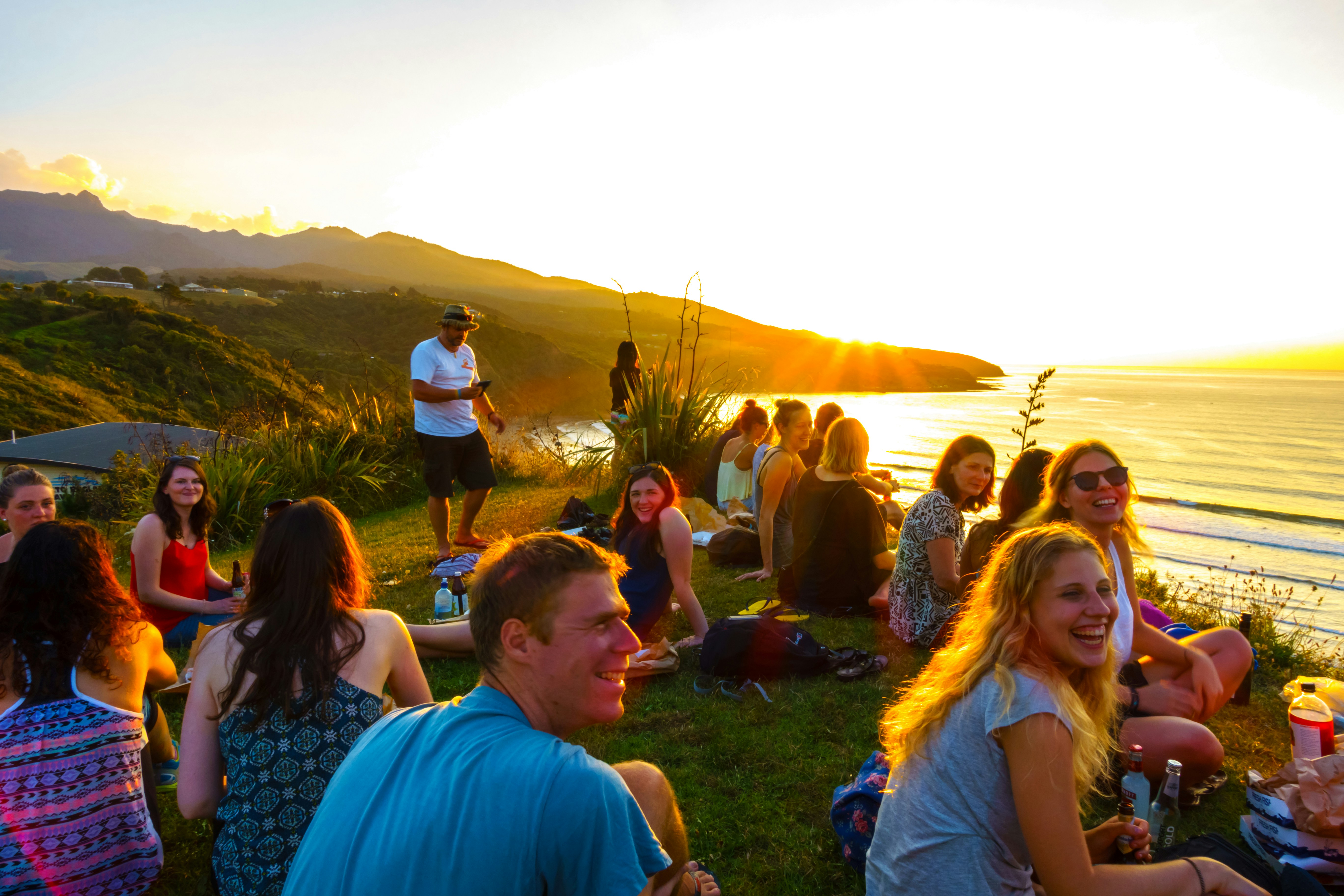 Community gathering at sunset with mountains and ocean